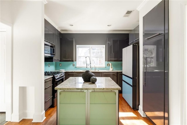 kitchen with stainless steel appliances, light wood-type flooring, a sink, and decorative backsplash