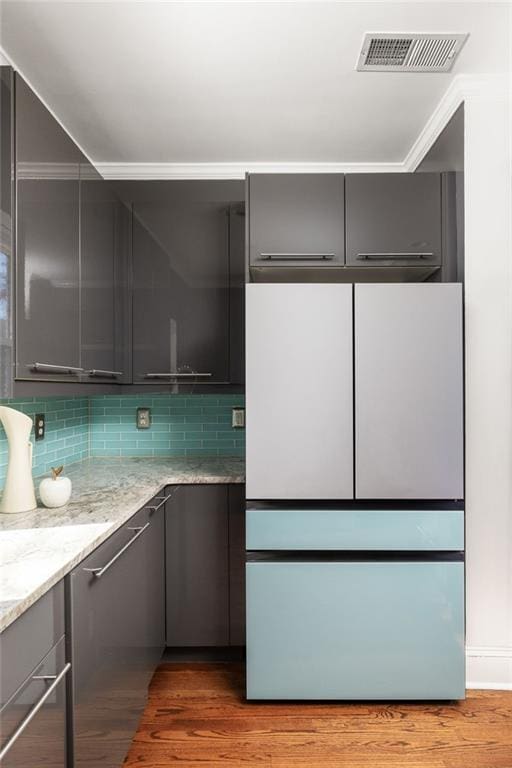 kitchen with light stone counters, light wood finished floors, visible vents, decorative backsplash, and gray cabinetry