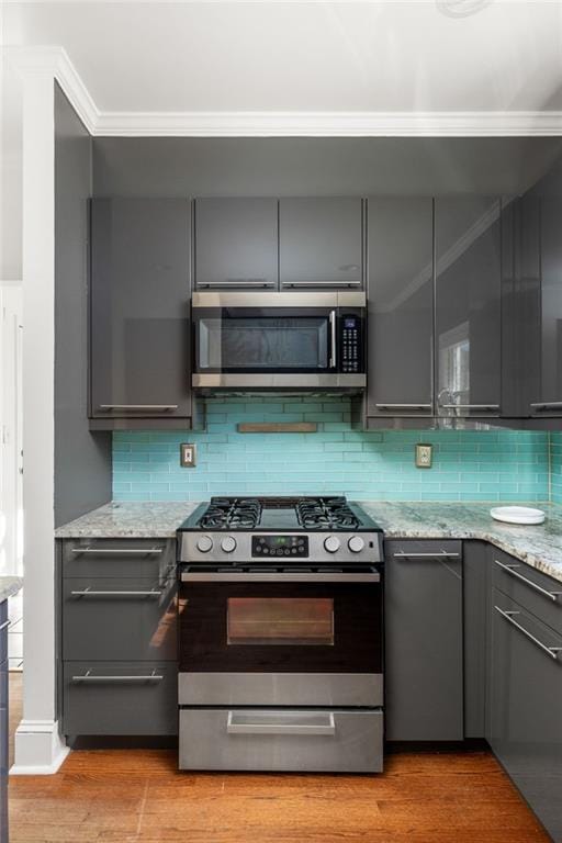 kitchen featuring ornamental molding, appliances with stainless steel finishes, gray cabinets, and light wood-style floors