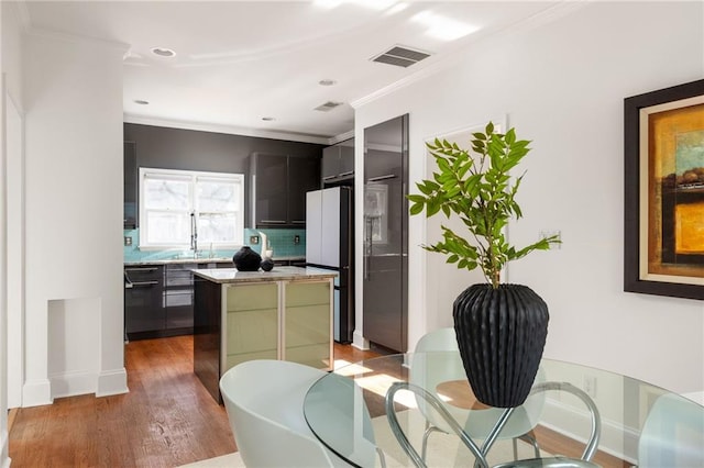 kitchen featuring visible vents, a kitchen island, wood finished floors, freestanding refrigerator, and light countertops