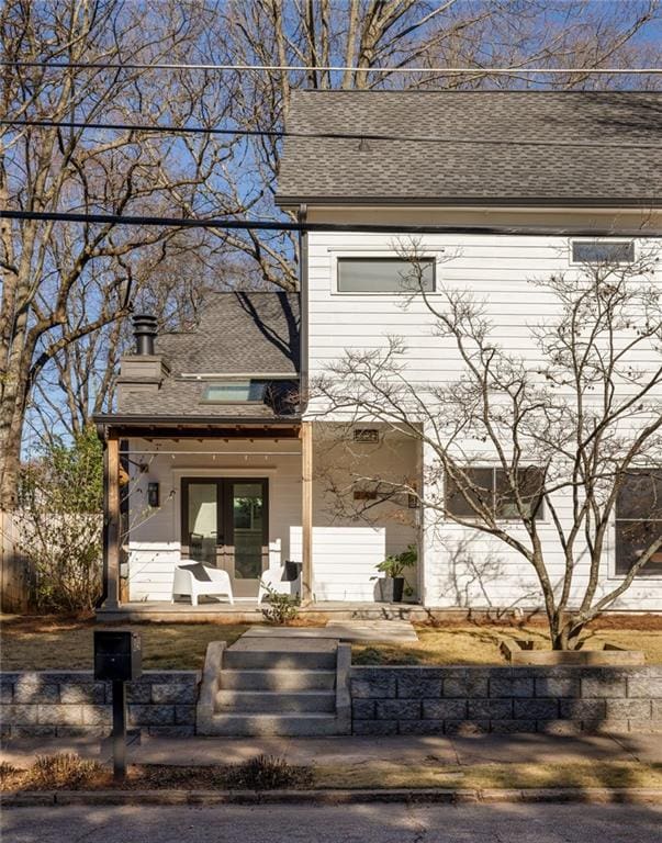 exterior space with a porch and roof with shingles