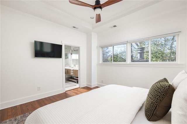 bedroom with crown molding, visible vents, a raised ceiling, and wood finished floors