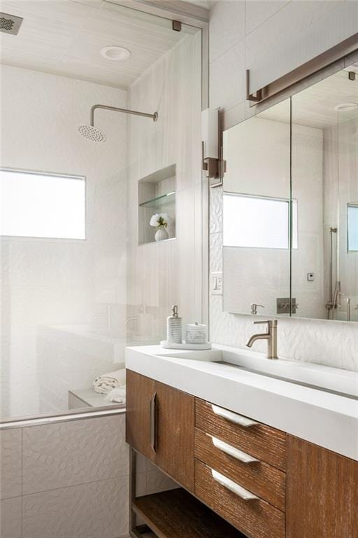 bathroom with tile walls, visible vents, a tile shower, and vanity