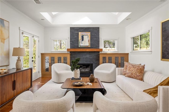 living area with a skylight, a fireplace, crown molding, and wood finished floors