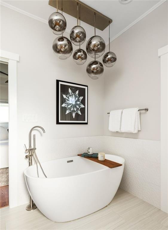 full bath with tile walls, ornamental molding, a freestanding bath, and wainscoting