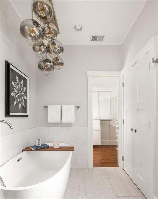 full bath with a soaking tub, visible vents, tile walls, and a wainscoted wall