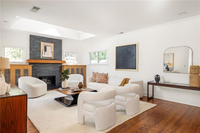 living area with a raised ceiling, visible vents, a fireplace, and wood finished floors