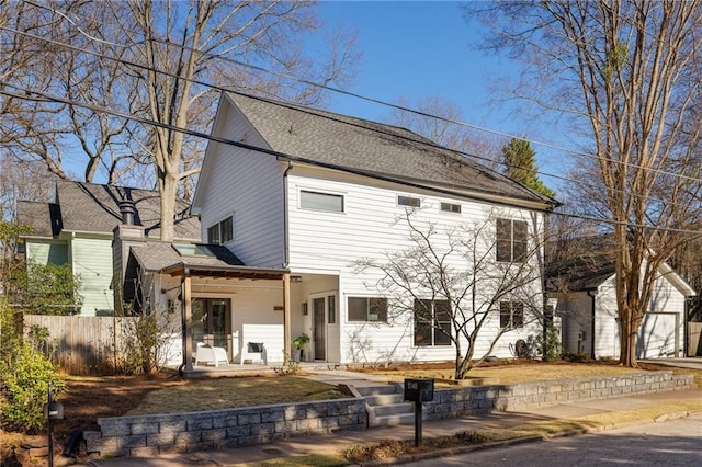 view of front facade featuring a shingled roof and fence