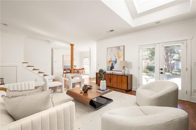 living area with a skylight, wood finished floors, visible vents, and crown molding