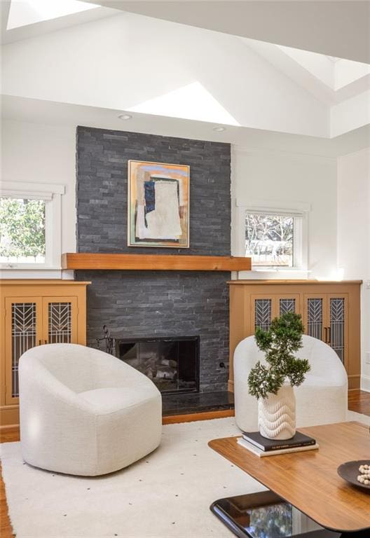 living area featuring a fireplace, high vaulted ceiling, and wood finished floors