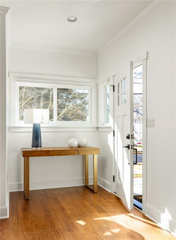 interior space featuring ornamental molding, light wood-type flooring, and baseboards