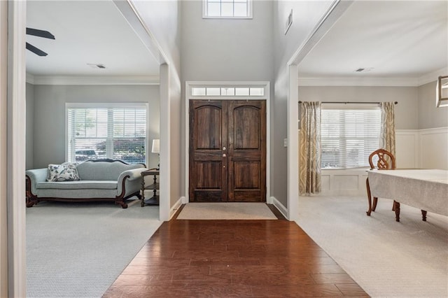 foyer entrance featuring plenty of natural light, wood finished floors, crown molding, and a ceiling fan