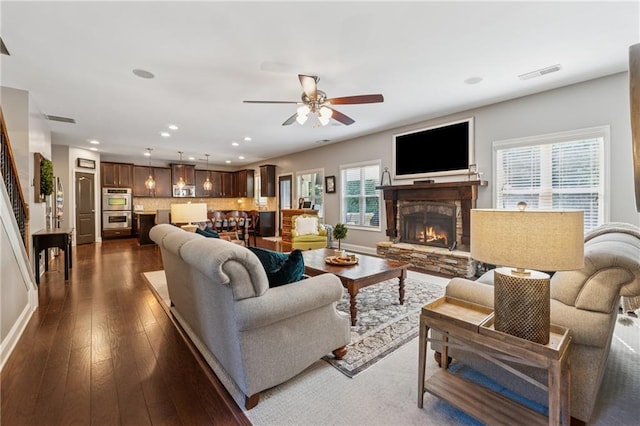 living area featuring recessed lighting, dark wood-type flooring, a ceiling fan, a fireplace, and baseboards