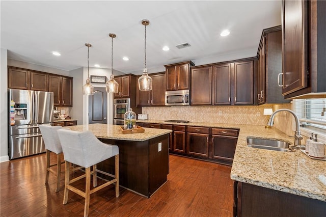 kitchen with appliances with stainless steel finishes, a sink, dark brown cabinetry, a center island, and recessed lighting