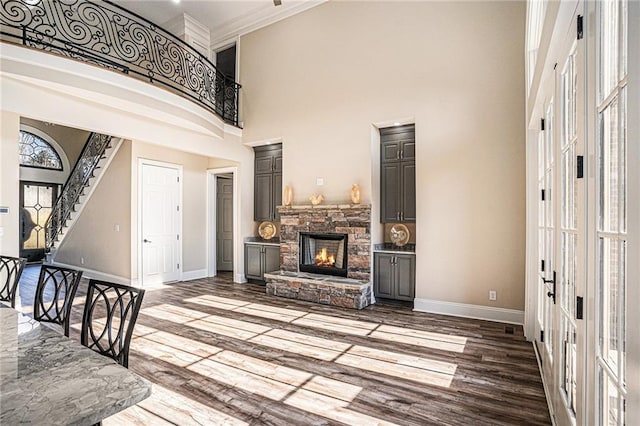 entrance foyer with hardwood / wood-style floors, a fireplace, crown molding, and a high ceiling