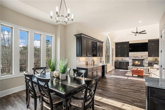 dining space with a fireplace, dark hardwood / wood-style flooring, ceiling fan with notable chandelier, and sink