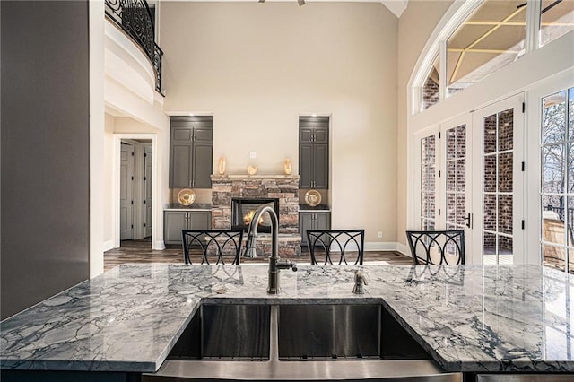 kitchen with a fireplace, a high ceiling, light stone counters, and sink