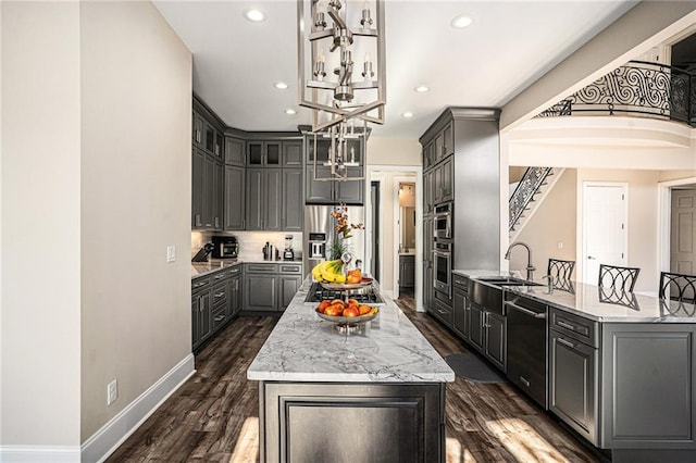 kitchen featuring a center island, gray cabinets, light stone countertops, appliances with stainless steel finishes, and dark hardwood / wood-style flooring