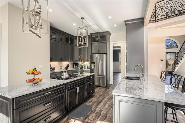 kitchen featuring a kitchen island with sink, sink, appliances with stainless steel finishes, and dark wood-type flooring