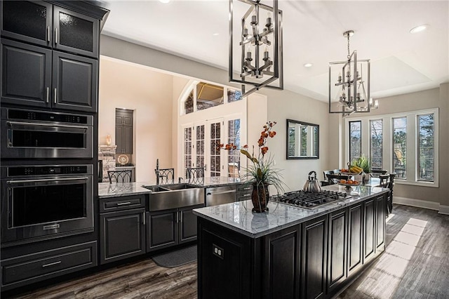 kitchen with light stone countertops, a center island, stainless steel appliances, and dark hardwood / wood-style floors