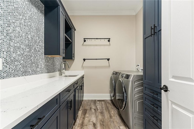 laundry room featuring sink, wood-type flooring, ornamental molding, and independent washer and dryer