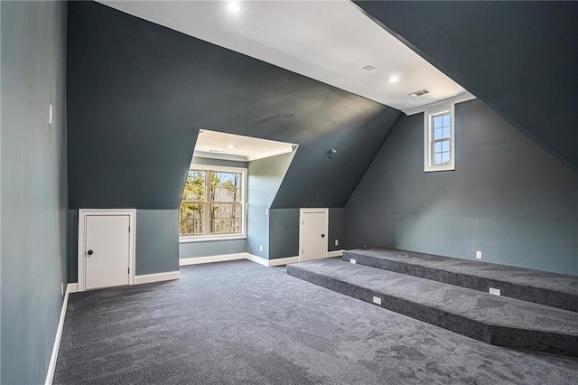 bonus room featuring a wealth of natural light, dark carpet, and vaulted ceiling