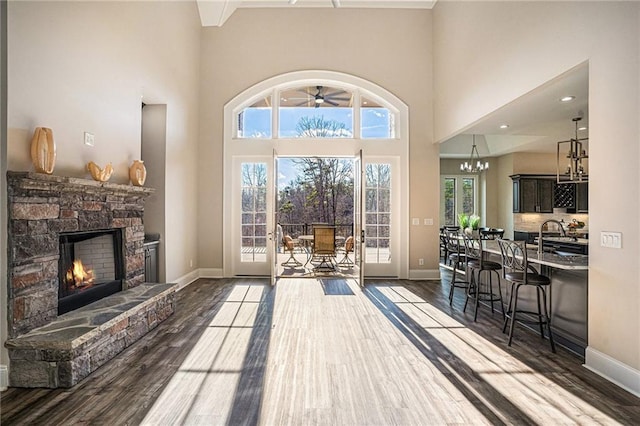 interior space featuring a fireplace, a high ceiling, dark wood-type flooring, and a notable chandelier