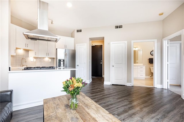 kitchen featuring backsplash, white cabinetry, dark wood-type flooring, stainless steel fridge, and island range hood