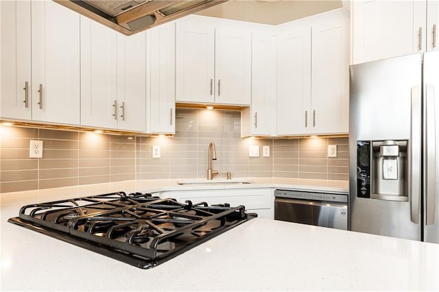 kitchen with sink, backsplash, white cabinets, and stainless steel appliances