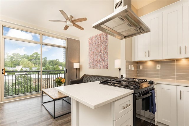 kitchen featuring island exhaust hood, white cabinetry, and black gas range oven