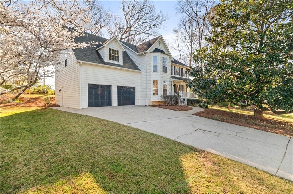 view of front facade with driveway, a garage, and a front lawn