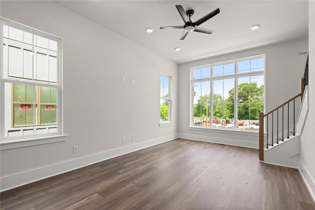 unfurnished room featuring a healthy amount of sunlight, baseboards, and dark wood-style flooring