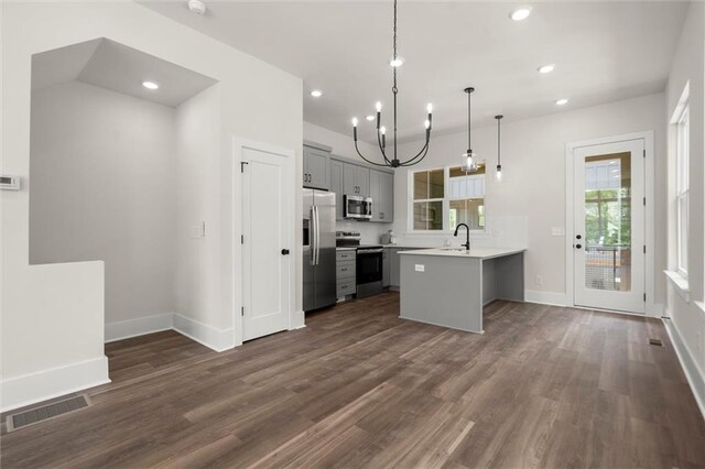 kitchen with appliances with stainless steel finishes, an inviting chandelier, a sink, visible vents, and gray cabinetry