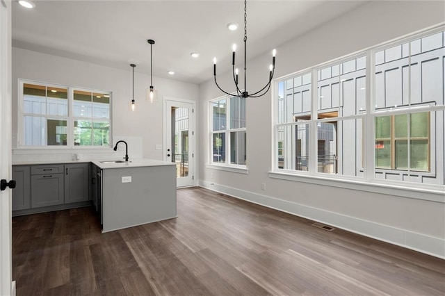 kitchen featuring a notable chandelier, a sink, light countertops, recessed lighting, and dark wood-type flooring