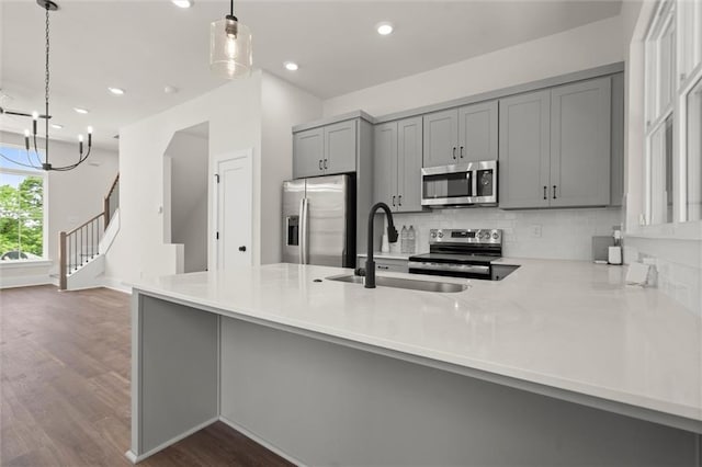 kitchen featuring a sink, light countertops, gray cabinets, stainless steel appliances, and dark wood-type flooring