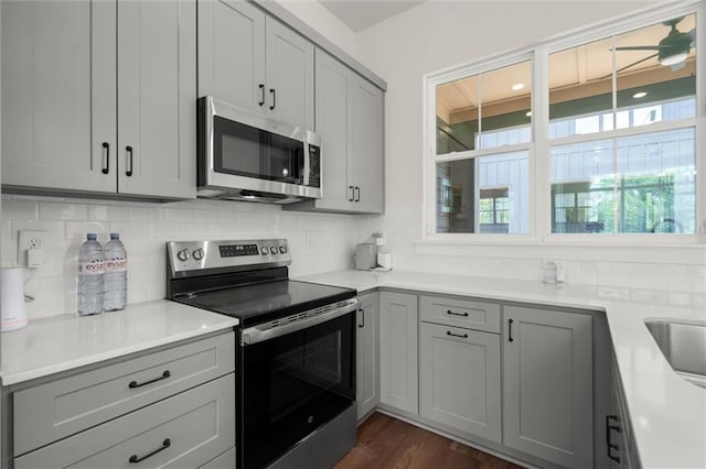 kitchen with light countertops, appliances with stainless steel finishes, gray cabinets, and tasteful backsplash