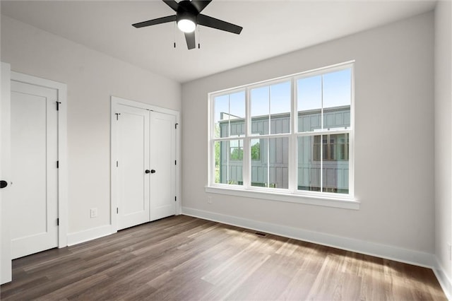 unfurnished bedroom with baseboards, visible vents, wood finished floors, and a closet