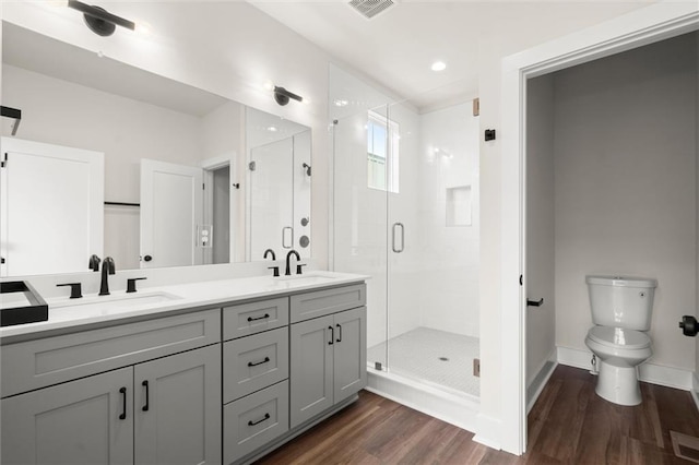 full bath featuring a stall shower, visible vents, a sink, and wood finished floors