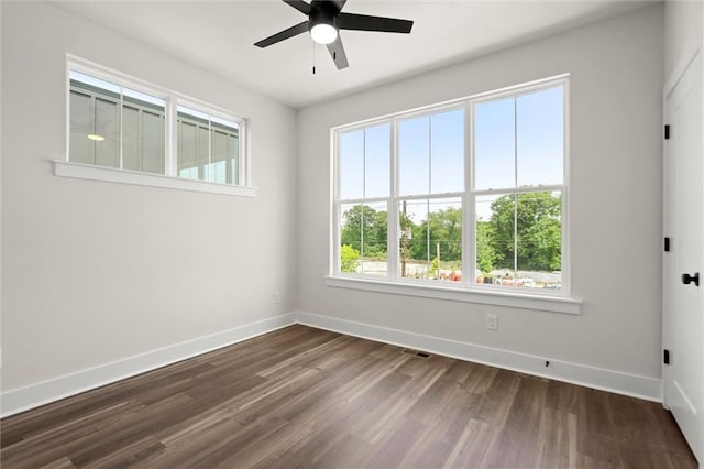unfurnished room featuring baseboards, ceiling fan, visible vents, and dark wood-type flooring
