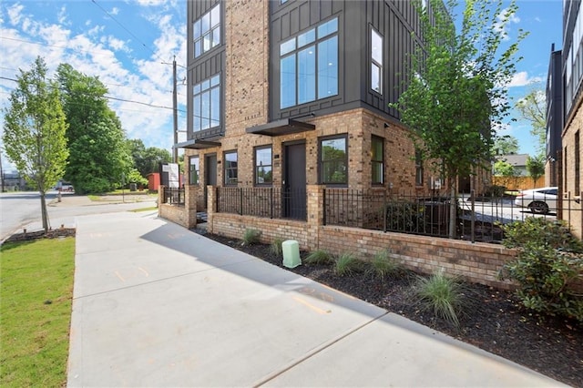 view of home's exterior with fence private yard, board and batten siding, and brick siding