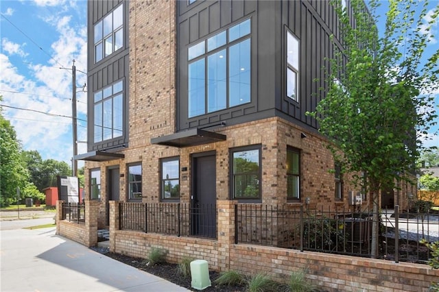 exterior space with fence, board and batten siding, and brick siding