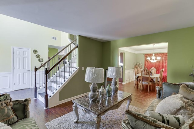 living room featuring wood-type flooring, a chandelier, and ornamental molding