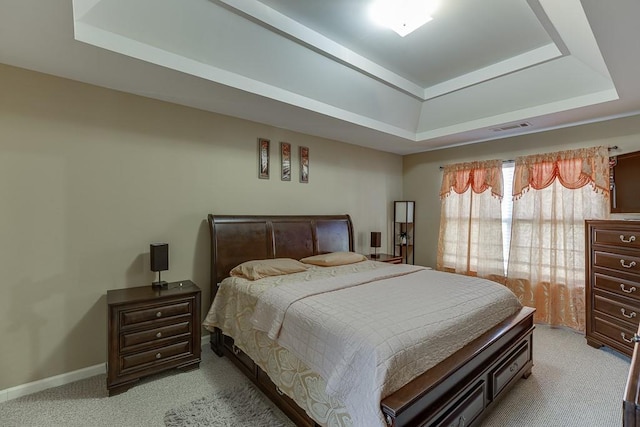 bedroom featuring light colored carpet and a tray ceiling