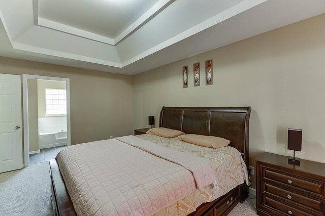 carpeted bedroom with ensuite bath and a raised ceiling