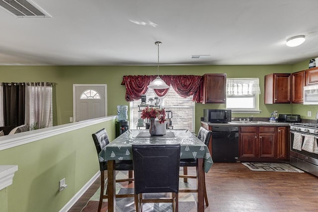 kitchen with black appliances, dark wood-type flooring, sink, and pendant lighting