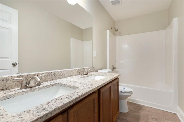 5712 Grande River Rd, Atlanta, GA 30349 - bathroom featuring toilet, shower / bathtub combination, wood finished floors, and double vanity