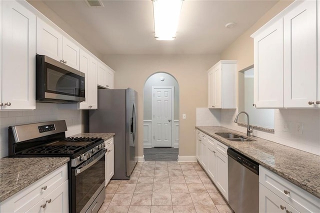 5712 Grande River Rd, Atlanta, GA 30349 - kitchen with appliances with stainless steel finishes, a sink, tasteful backsplash, white cabinets, and arched walkways