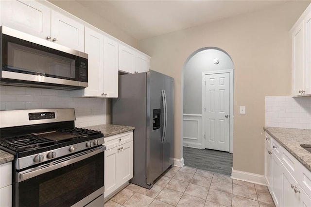 5712 Grande River Rd, Atlanta, GA 30349 - kitchen with appliances with stainless steel finishes, white cabinetry, light tile patterned flooring, light stone countertops, and decorative backsplash