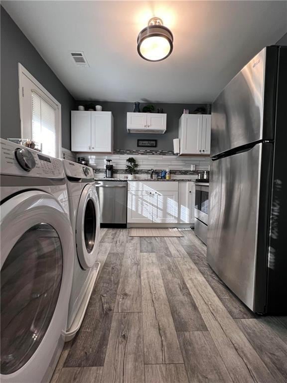 clothes washing area featuring wood-type flooring and washing machine and dryer