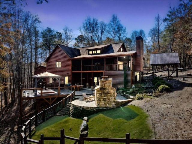 back of house with a gazebo, a patio area, a sunroom, and an outdoor fireplace